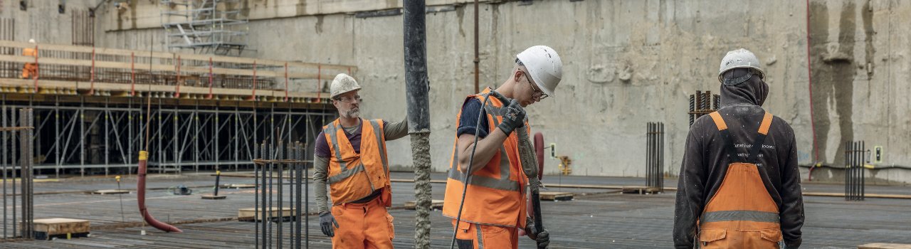 Drie bouwvakkers storten beton