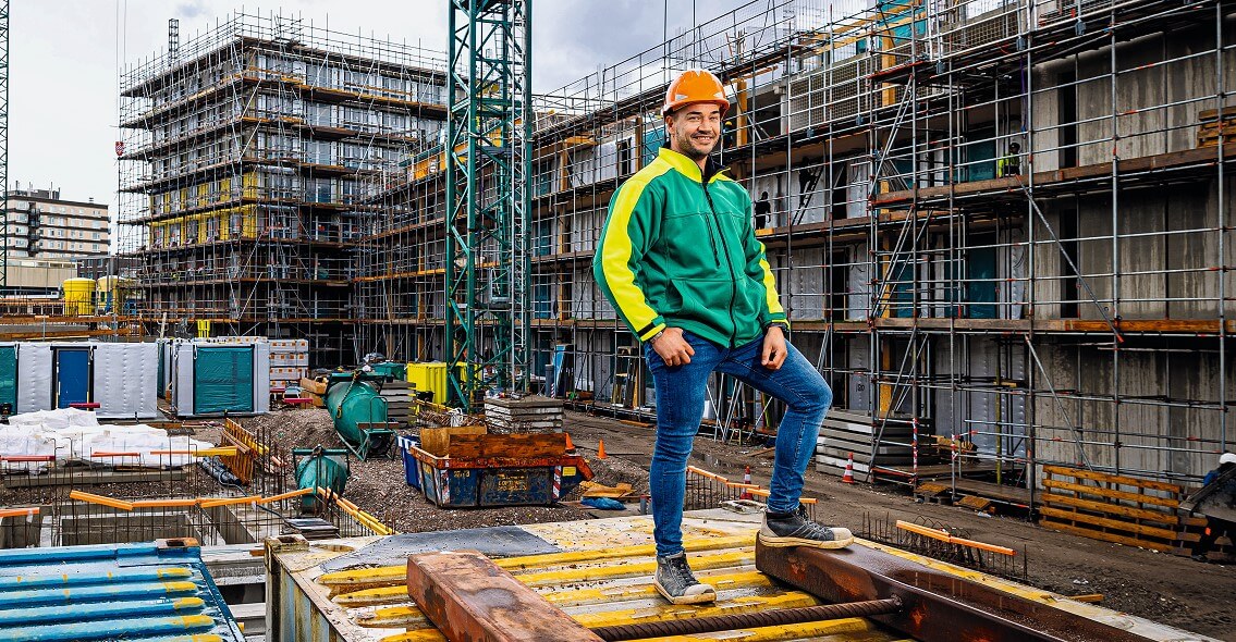 Bouwvakker staat op een bouwplaats van een appartementencomplex
