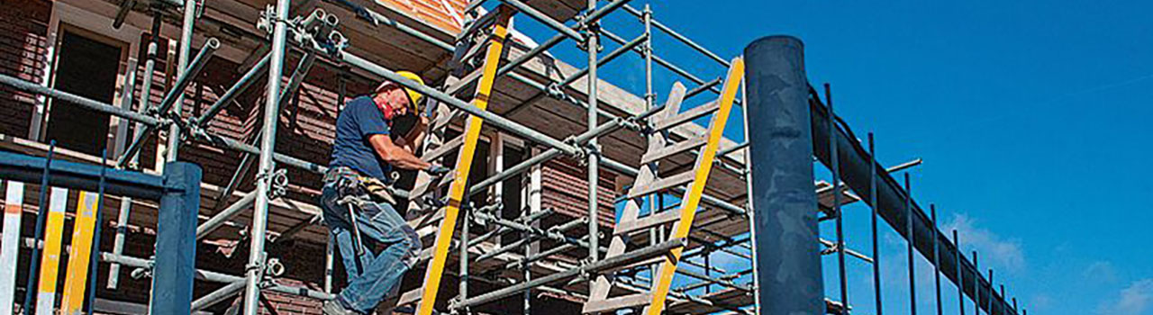 Bouwvakker op ladder in steiger bij nieuwbouwwoning