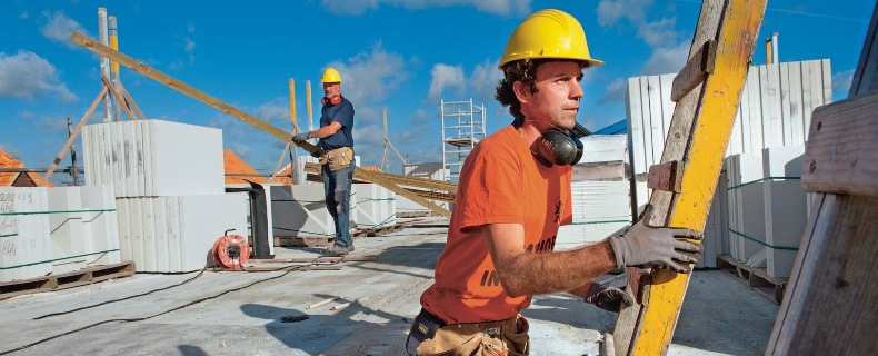 Bouwvakker staat bij een ladder op een dak in de buurt van een collega