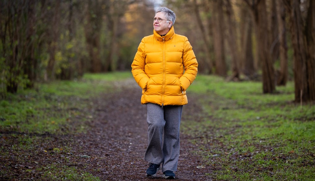 Clara van Duin loopt door het bos in een gele winterjas